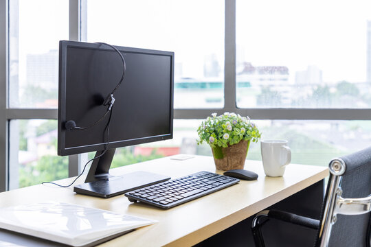 Call center desk with computer, headset, coffee mug, and potted plant in modern office