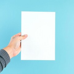 Obraz premium Hand holding blank white paper against a bright blue background