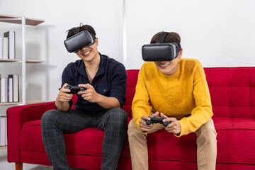 Asian LGBT gay couple playing virtual reality game together with VR headset and controllers