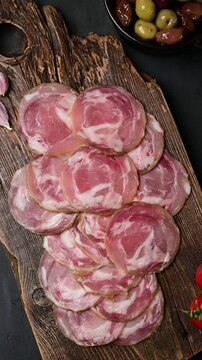 Succulent sliced coppa capocollo display with rosemary garnish and mixed olives