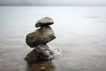 A pile of stones in the water of a mountain lake, minimalism.
