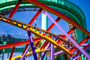 Roller coaster with complex structure of colorfully painted rails and colorful fairy lights in an...