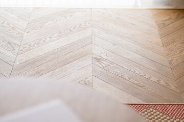 Chevron wood flooring close-up — light oak herringbone parquet pattern, minimalist Scandinavian interior, elegant natural texture for modern luxury home, sunlit stylish floor design