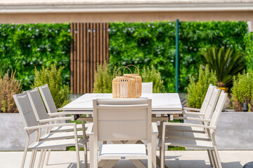 Modern outdoor dining area with white furniture and lush greenery — stylish garden setup for luxury lifestyle, alfresco meals and premium home design inspiration