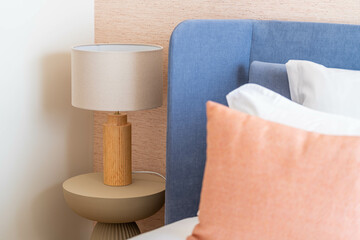 Elegant bedroom detail with pastel pillows and wood lamp — modern soft minimalism, cozy home interior, light Scandinavian style, blue headboard and tactile textures