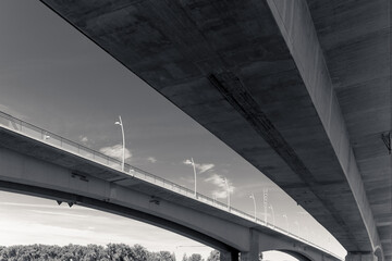 Majestic concrete bridges stretch across the serene landscape under a brilliant blue sky dotted...