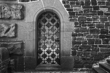 Rustic wooden door with diamond pattern nestled in ancient stone wall exudes timeless charm and...