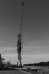 Industrial crane towers over the serene waterfront, capturing the essence of maritime life in a...