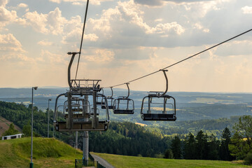 Chairs glide above lush hills under a cloudy sky in a scenic mountain landscape inviting adventure and exploration