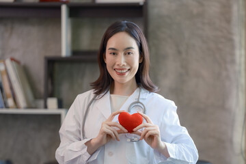 Asian female doctor holding a red heart in her hands in the concept of care your heart.