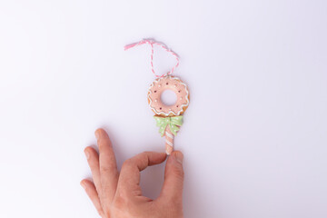 Close-up of a hand holding a donut decorated with pink and green ribbon, isolated on a white background. Perfect for bakery, festive, and celebration designs.