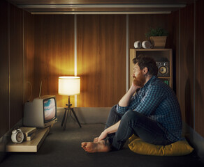 Bored man watching TV in a small dark room