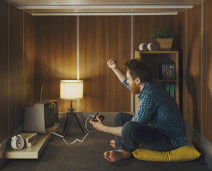 Cheerful man playing video games in a tiny living room