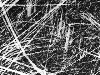 Intricate patterns created by scratches on a textured black surface during daylight hours