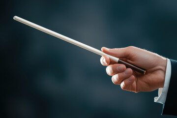 A conductor's hand grasps a white baton with confidence, showcasing subtle vein details. The dark wooden handle adds an element of elegance, embodying authority and finesse in orchestral leadership.