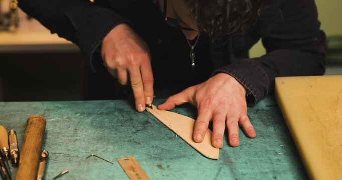 Craftsman making holes in leather using a stitching groover in a traditional workshop