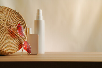 Elegant arrangement of a bag, sunglasses, and cosmetic spf bottles on a simple beige backdrop....