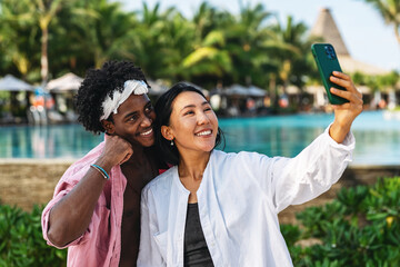 Diverse couple connected, embracing technology and social media while enjoying moments at the beach