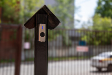 Gate access button with blue LED indicator on house-shaped control post