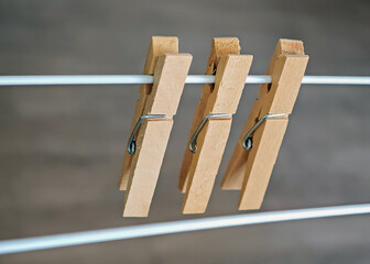 Three Wooden Clothespins Attached to a Wire with Neutral Background