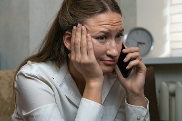 Young woman looking concerned while receiving upsetting news during phone call, her face showing worry and stress as she listens intently