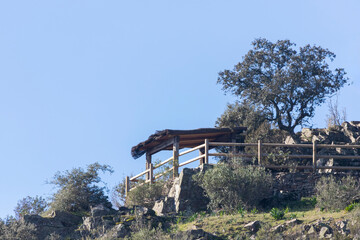 Rustic wooden viewpoint on Cerro Gimio trail, Monfragüe Natural Park, Spain. Surrounded by rocks, oaks and Mediterranean vegetation under clear blue sky