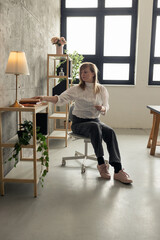 Woman reaching for book in home office with concrete wall