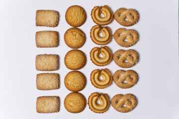 Assorted Danish butter cookies arranged on a white background, sprinkled with sugar crumbs. A classic selection featuring various shapes and textures, perfect for snack or dessert concepts.