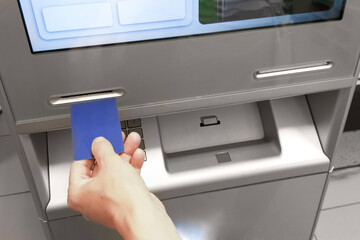 Bank card in hand. Inserts credit card into ATM.