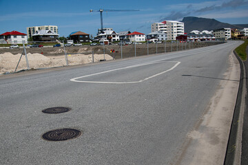 Fototapeta premium Scenic suburban Akranes road with modern housing and a mountain background