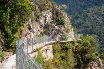 Fototapeta premium Scenic view of surrounding mountains and picturesque village from a hiking trail along an old irrigation ditch in Frigiliana, Spain.