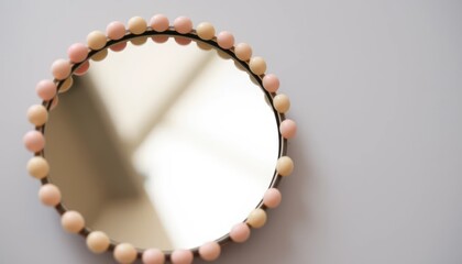 Round mirror with beaded trim, hanging on a white wall, home decor
