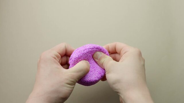 Hands stretching and molding squishy purple floam or glitter slime, closeup