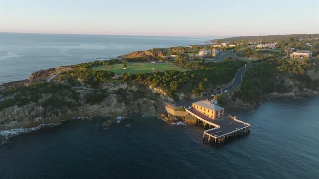 Aerial: Drone flying a 360 around Tathra Wharf during golden hour sunrise, South Coast NSW, Australia
