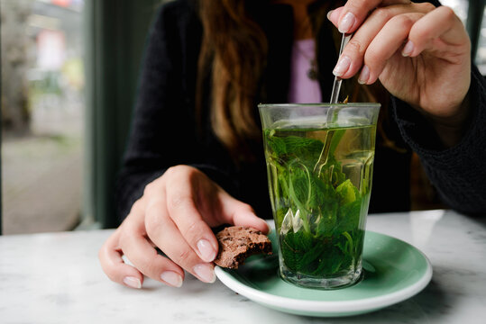 Close-up of mint tea and cookie with hands at Alkmaar café