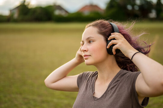 Young gen z girl with headphones, outdoor portrait, copy space
