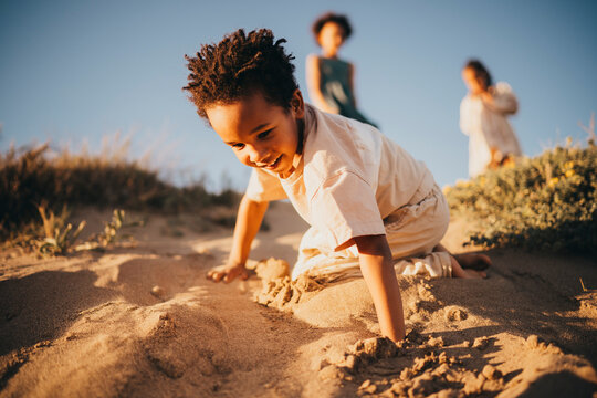 Black boy girl running around sand dunes at beach sunset fun