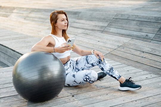 Woman in Athletic Wear with Yoga Ball and Smartphone