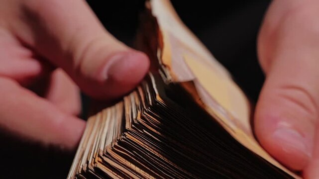 Macro scene shows thick wad of euro cash flipped by fingers in focused detail
