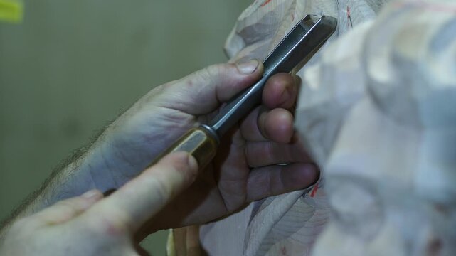 Macro view of skilled hands using a sharp chisel to carve fine details into a wooden sacred statue, showing the precision and texture of traditional sculpture craftsmanship in religious artwork.