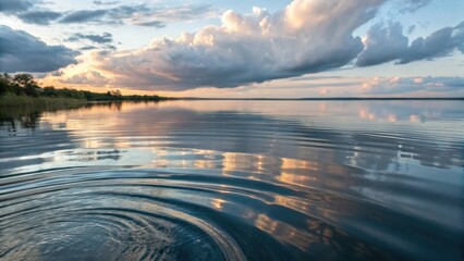 Serene Lakeside Sunset with Ripples on the Calm Water Surface and Dramatic Clouds