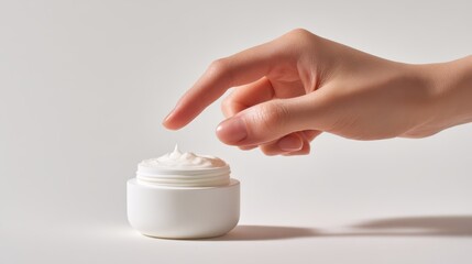 A hand delicately touches a jar of moisturizing cream