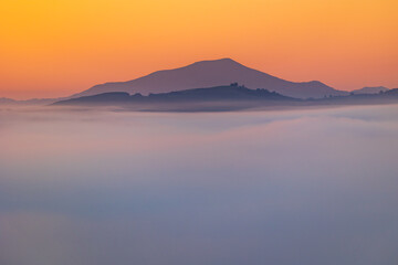 Obraz premium Mountains of the La Rhune Range Emerging from a Sea of Clouds at Sunrise in Sare