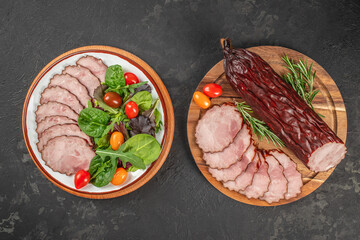 Two beautifully arranged plates display sliced cured meat with vibrant leafy greens, cherry...