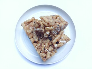 Delicious and sweet sachima cake on white plate with white and black sesame isolated on white background,sweet snacks from China