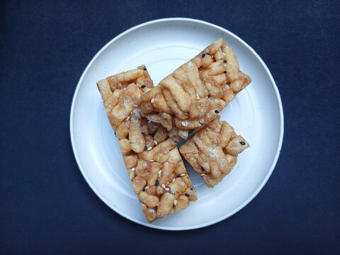 Delicious and sweet sachima cake on white plate with white and black sesame isolated on black background,sweet snacks from China