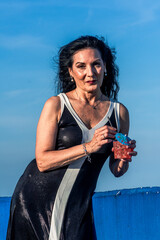 Elegant senior model enjoying a cocktail outdoors with blue sky