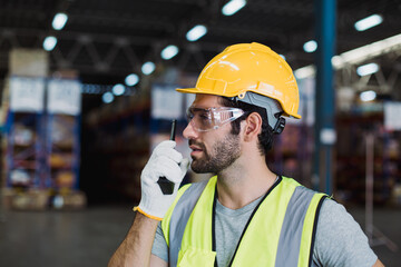 Warehouse worker coordinating truck shipments through walkie talkie, supporting road logistics, cargo tracking, and supply chain efficiency.
