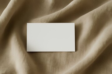 Mockup of blank business card placed on linen fabric with soft folds, elegant natural branding scene
