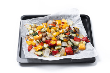 Roasted vegetables on a baking tray isolated on white on white background